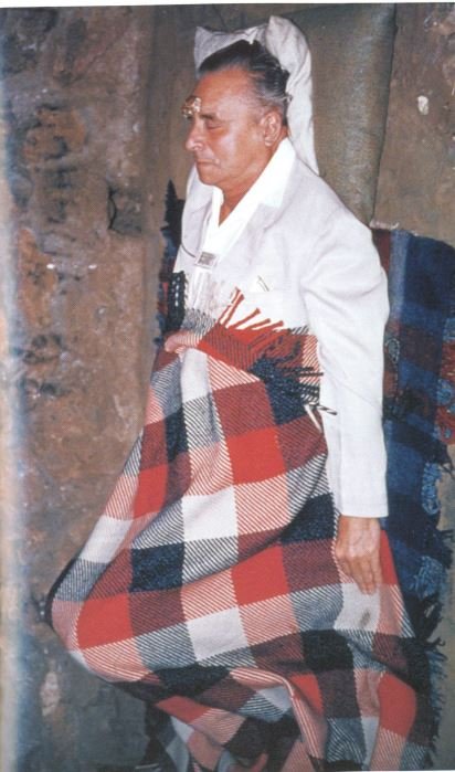 A person in a white shirt and red and black plaid blanket
AI-generated content may be incorrect.